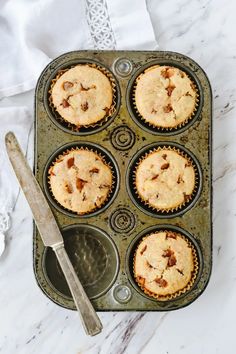 a muffin tin filled with cupcakes on top of a marble countertop