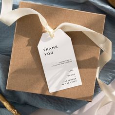 a thank you tag attached to a brown gift bag with white ribbon on top of it