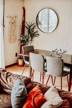 a living room filled with furniture and a round mirror on the wall over a table