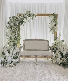 a white couch sitting in front of a floral arch