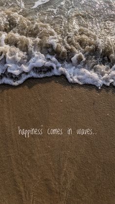 the words happiness comes in waves written on the sand at the ocean's edge