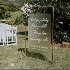 a sign that is on the grass in front of some white chairs and an apple tree