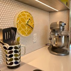 a kitchen counter with a mixer and a clock on the wall above it that is decorated with circles