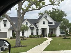 a large white house sitting next to a tree in front of a car door window