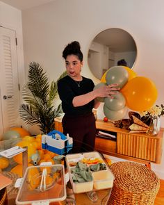 a woman standing in front of a table filled with oranges and other food items