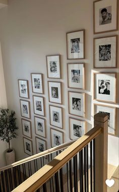 there are many framed pictures on the wall next to the bannister and stairs