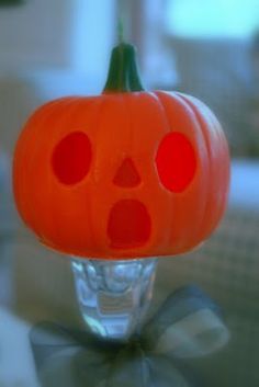 an orange plastic pumpkin with holes in it's mouth sitting on a glass table