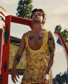 a man with tattoos standing in front of a carnival ride and looking up at the sky