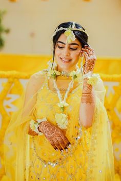 a woman wearing a yellow dress and holding her hands up to her face, smiling