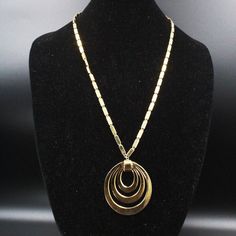 "DESCRIPTION: This designer necklace by Monet, dating back to the 1950s, embodies the era's classic style and sophistication. The piece showcases a striking gold tone medallion pendant that exudes an air of vintage elegance, skillfully matched with a complementary gold tone chain. The \"MONET\" mark certifies its authenticity and quality, reflecting the brand's longstanding reputation for timeless fashion. In excellent condition, this necklace has been impeccably preserved, allowing its wearer t Vintage Polished Pendant Necklace, Vintage Pendant Necklace With Polished Finish, Elegant Gold Medallion Necklace With Polished Finish, Retro Gold Medallion Jewelry, Formal Gold Medallion Necklace With Round Pendant, Vintage Gold-tone Round Pendant Jewelry, Gold-tone Metal Medallion Necklace, Gold-tone Medallion Necklace, Gold-tone Medallion Metal Necklace