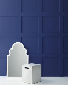 a white box sitting on top of a table next to a mirror and blue wall