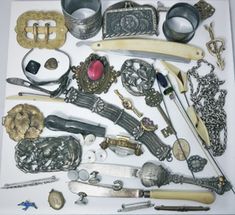 an assortment of silver items are displayed on a white table top with other metal objects