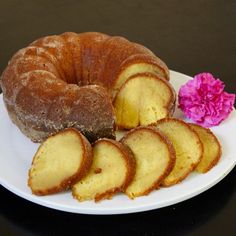 a bundt cake on a plate with slices cut out next to it and pink flower