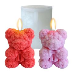 two small teddy bears with candles in the shape of roses on them, sitting next to each other