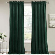 a green curtain hanging in front of a window with a white rug on the floor