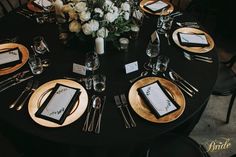 a black table with gold plates and place settings