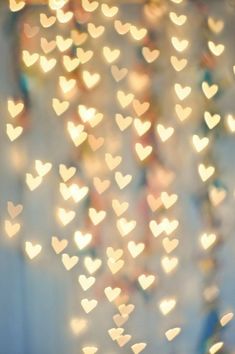 some white hearts hanging from the ceiling in front of a wall with blurry lights