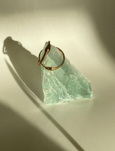 a gold ring sitting on top of a piece of green glass next to a shadow