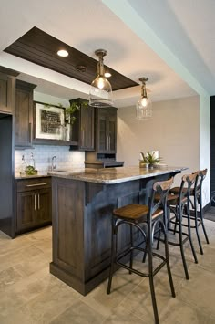 a kitchen with an island and four bar stools in front of the counter top