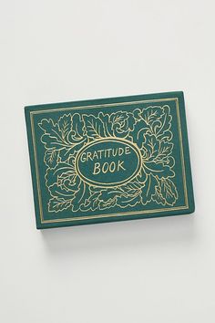 a green and gold book sitting on top of a white table