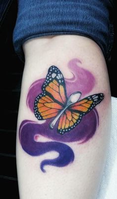 a colorful butterfly tattoo on the left side of the leg, with purple and orange swirls around it