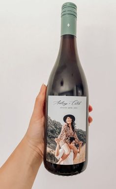 a hand holding a bottle of wine with a woman's photo on the label