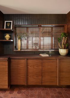 a kitchen with wooden cabinets and tile flooring next to a window covered in shutters