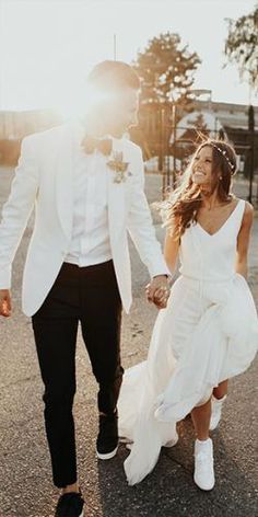 a bride and groom walking down the street holding hands