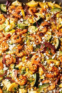 a pan filled with shrimp, zucchini and red onion stir fry on top of rice