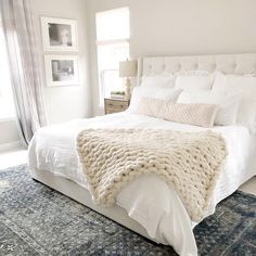 a large white bed sitting in a bedroom on top of a blue and white rug