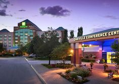 the entrance to a hotel at night with lights on and flowers growing in the foreground