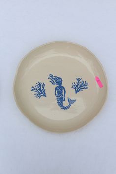 a white plate with blue designs on it next to a pink marker that says mermaid