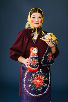 a woman in a colorful dress holding a matzoka doll and a small toy