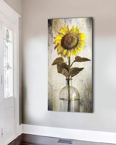 a sunflower in a glass vase on a wall above a wooden floor and door