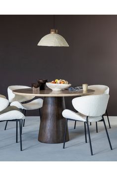 a dining room table with white chairs and a bowl of fruit on the center piece