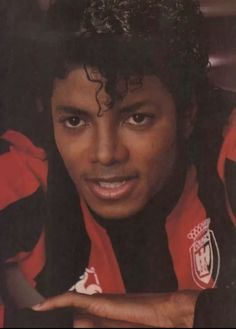 a close up of a person wearing a red and black shirt with his hand on his hip