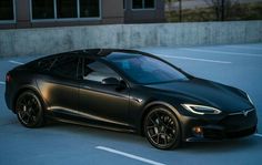 a black tesla car parked in front of a building with no doors on it's sides