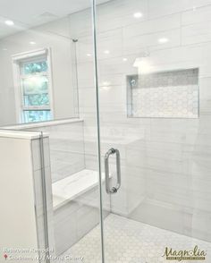 a glass shower door in a white bathroom