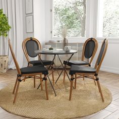 a round table with four chairs around it in a living room next to a potted plant