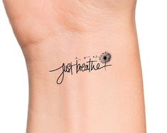 a wrist tattoo with the word just breathe on it's left arm and dandelion