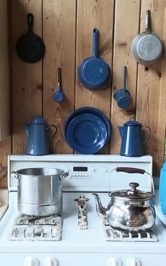 a stove with pots and pans hanging on the wall