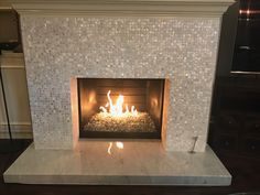 a fireplace that is lit up in the middle of a living room with tile on it