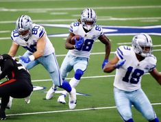 a football player running with the ball in his hand and another person kneeling on the ground behind him