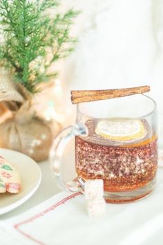 a glass mug filled with liquid sitting on top of a table next to some cookies