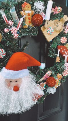 a christmas wreath with santa clause and candy canes hanging on it's front door