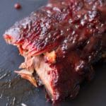 ribs covered in bbq sauce sitting on top of a cutting board