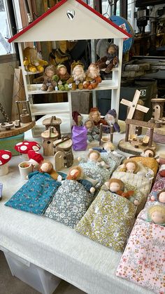 a table topped with lots of different types of cloth covered doll houses and figurines