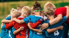 a group of young people standing next to each other on top of a soccer field