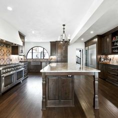 a large kitchen with wooden floors and dark wood cabinetry, along with an island in the middle