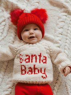 Show your holiday spirit with our Santa Baby Sweater! Hand-knit in chunky yarn, this crew neck sweater in Natural says 'Santa Baby' across the front in Red yarn. Hand knit, it is soft and warm. This is such a great gender neutral sweater, perfect for any little person. Make sure you buy the matching Santa Baby hat to go with this.Our sweaters are partially knit from recycled, sustainable Polyester yarn made from plastic bottles. We are on a mission to help reduce the world's plastic pollution pr Baby Christmas Sweater, Neutral Sweater, Neutral Sweaters, Pull Bebe, Blanket Sweater, Baby Bonnets, Red Yarn, Baby Sweater, Plastic Pollution